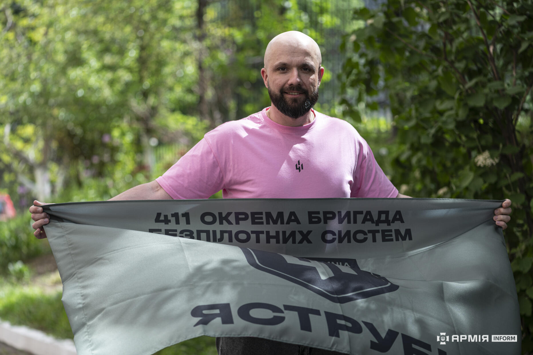 Ігор Завгородній тримає в руках знамено 411-ї окремої бригади безпілотних систем