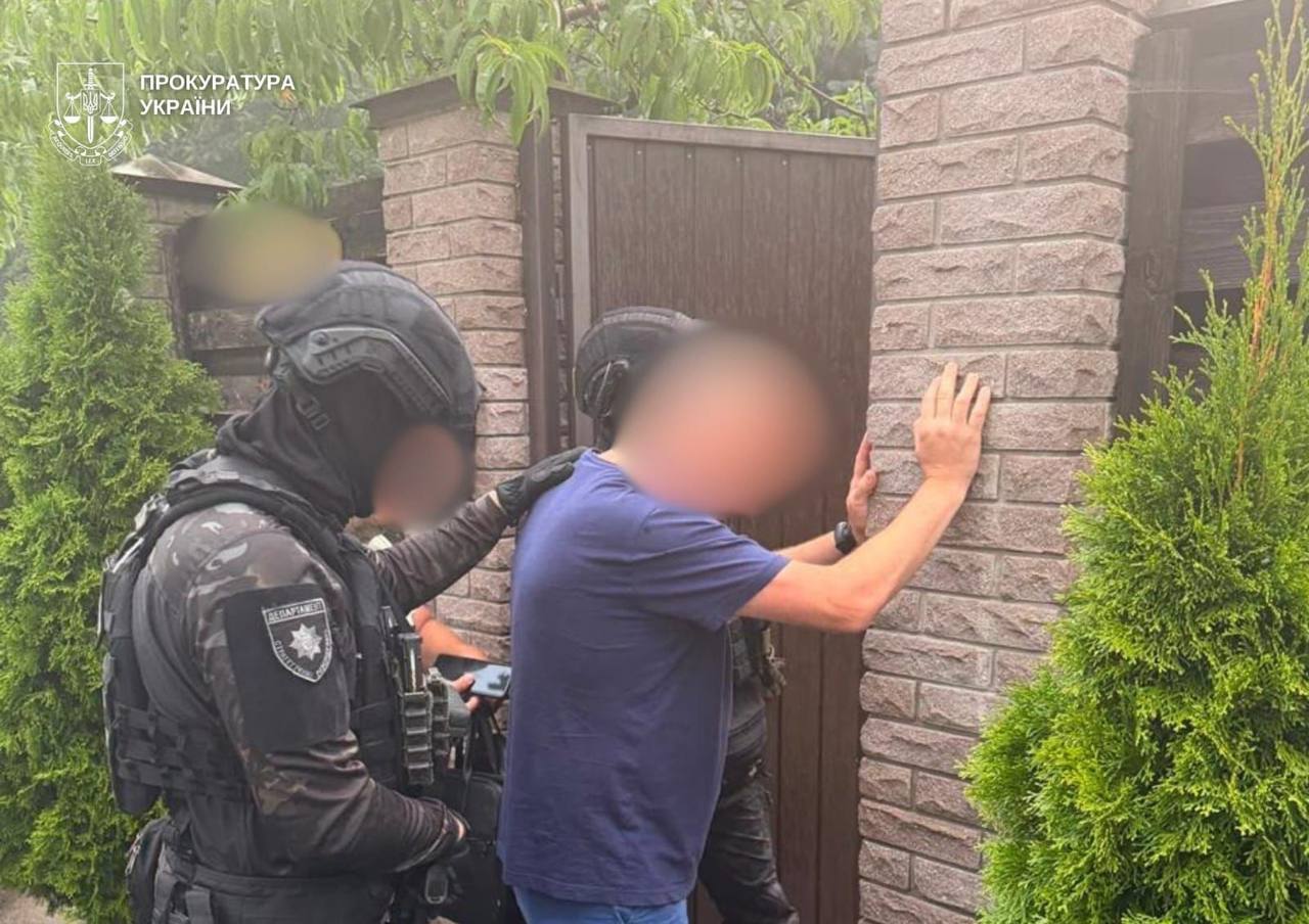 Затриманий стоїть обличчям до паркану