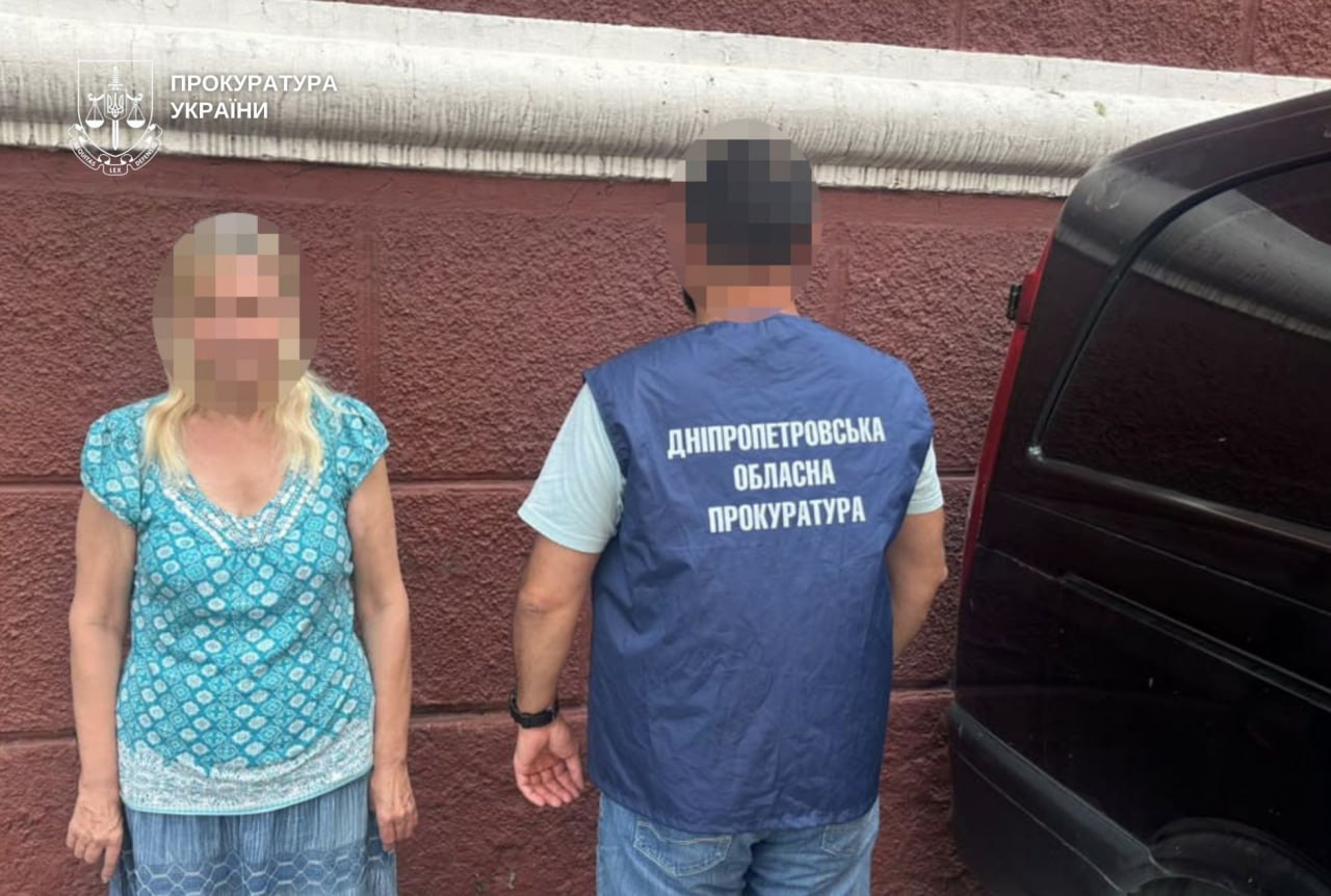 Затримана жінка стоїть біля правоохоронця